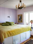 A double bed with storage space underneath behind frosted glass in a simple bedroom