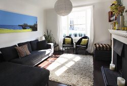 A living room with black seats, a beige flokati rug and a fireplace