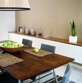 A bowl of green apples on a wooden dining table