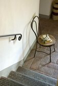 A chair next to a flight of stairs in a hallway with a terracotta floor