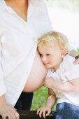 A little girl listening to her pregnant mother's belly