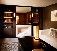Classic modern gentleman's study with white sofa in front of dark brown wall and chimney beside built-in book shelves
