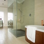 Begehbare Dusche mit Glaswand neben einer frei stehenden Badewanne