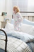 Little girl in pajamas standing on a bed