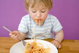 Kleiner Junge mit Spaghetti im Mund