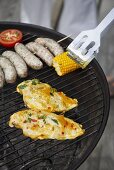Chicken, corncob and sausages on a barbecue