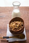 Muesli in wooden bowl, milk behind