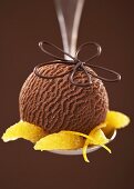 Chocolate ice cream with orange segments on a spoon