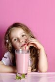 Small girl drinking strawberry milk through a straw