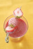 Strawberry smoothie with frozen strawberry skewer (overhead)