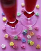 Heart-shaped sweets and two glasses of red cocktail