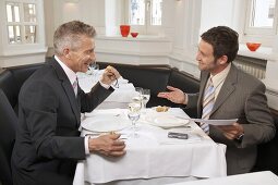Two men negotiating while eating in a restaurant