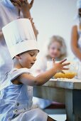 Little boy baking, siblings watching