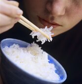 Person isst Reis mit Stäbchen