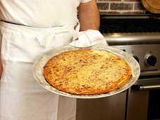 Koch serviert Käsepizza in der Küche