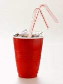 Cola mit Eiswürfeln und Strohhalmen im roten Becher