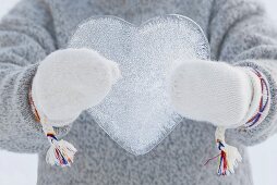 Person wearing mittens holding an ice heart