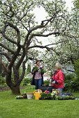 Two women planting up container in garden