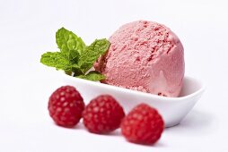 A scoop of raspberry ice cream and fresh raspberries