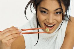 A young woman eating sweets with chopsticks