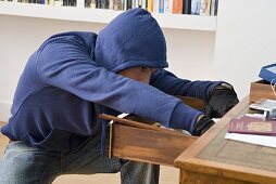 A burglar searching through a drawer
