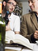 Two friends with books and bottles of wine at a wine tasting session