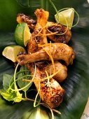 Asian chicken legs with limes on banana leaf