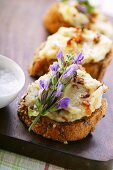 Toasted bread with white bean paste, bacon and flowers