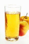 Glass of apple juice beside two fresh apples