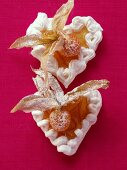 Two meringue hearts with physalis and icing sugar