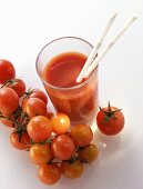 Glas Tomatensaft mit Strohhalmen; frische Kirschtomaten