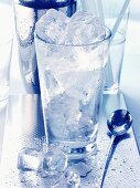 Eiswürfel im Glas vor Cocktailshaker
