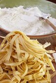 Home-made tagliatelle and flour on wooden chopping board