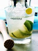 Caipirinha with ice cubes; wooden pestle