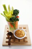 Celery, carrots and broccoli in glass beside dip