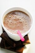 Cocoa in paper cup with straw on pieces of chocolate