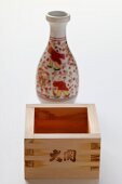 Square wooden sake bowl in front of carafe