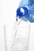 Wasser aus Plastikflasche in ein Glas gießen