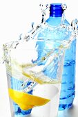 Zitrone fällt in Glas Mineralwasser