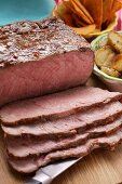 Roast beef on chopping board; tortilla chips