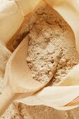 Wholemeal flour in sack with wooden scoop