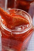 Strawberry jam in jar with kitchen spoon