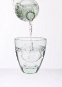 Wasser aus Flasche in Glas gießen