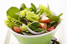 Spring salad with red onions and strawberries in bowl