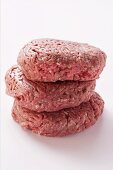 Three raw burgers in a pile