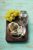 Roquefort with cheese dome and green grapes on chopping board