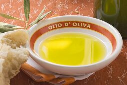Olivenöl in Schale auf Serviette, Olivenzweig, Weißbrot