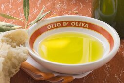 Olive oil in bowl on napkin, olive branch, white bread