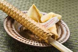 Fortune cookies and chopsticks in woven wrapper on plate