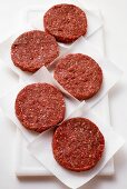 Five raw burgers on paper
